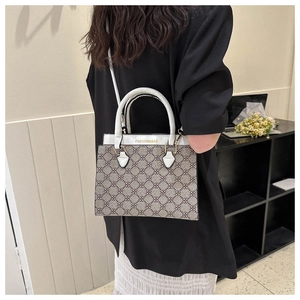 Detail view of brown clover print handbag with white handles and fashion and bag text