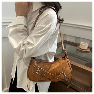 Gros plan du sac croissant en cuir caramel avec boucles métalliques porté par le mannequin