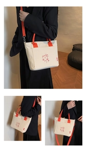 Detail of cream canvas tote bag with orange straps and cute cartoon bear graphic print