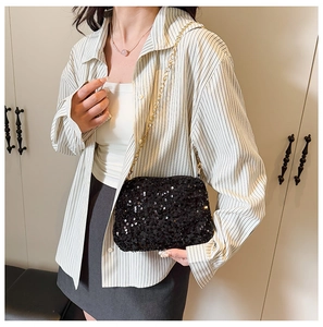 Close-up of stylish black sequin shoulder bag with elegant gold metal chain strap