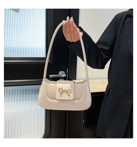 Close-up of golden bow metal buckle on a minimalist cream white shoulder bag