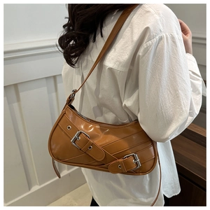 Caramel crescent shoulder bag with dual silver buckles shown on a model's arm