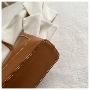 Détail du sac cabas en cuir marron avec surpiqûres blanches et finitions soignées