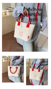 Detail of canvas tote bag showing red handles and cartoon bear print with side pockets