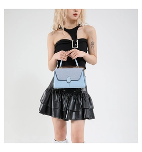 Detail view of light blue crossbody bag featuring woven texture flap and metallic buckle