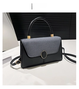 Detail of color-block handbag showing black leather and gray twill fabric with gold hardware