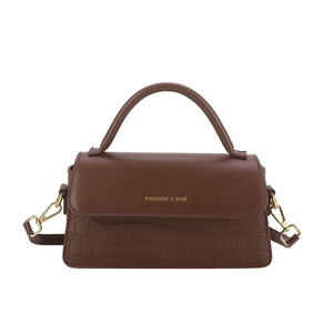 Brown faux leather handbag with crocodile texture and golden metal hardware on white background
