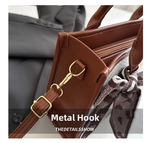 Detail of gold metal hook and leopard print silk ribbon on brown leather handbag