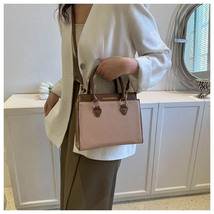 Detail of two-tone PU leather tote bag with gold hardware and top handle design