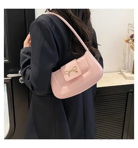 Photo de style d'un sac à bandoulière rose brillant avec un nœud doré sur un mannequin