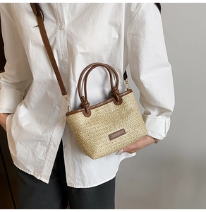 Détail d'un sac à main en paille tressée avec poignées en cuir marron sur modèle