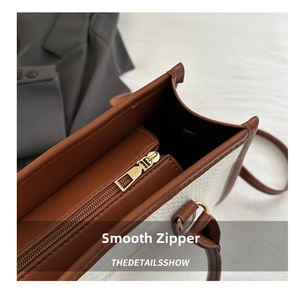 Close-up of the smooth metal zipper and internal compartment on the brown trimmed bag