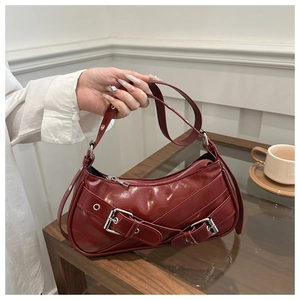 Detail of burgundy crescent bag with polished glossy leather and silver buckle strap