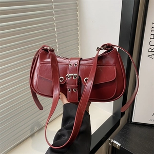 Dark red underarm bag with glossy finish and industrial belt buckle decor in sunlight