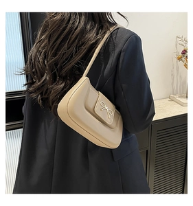 Détail du sac à bandoulière beige vintage avec boucle de nœud doré sur le rabat