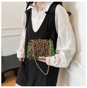 Gros plan d'un sac à bandoulière en paillettes colorées avec fine chaîne dorée sur mannequin