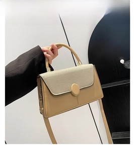 Detail view of khaki patchwork handbag featuring a large oval metal buckle and leather texture