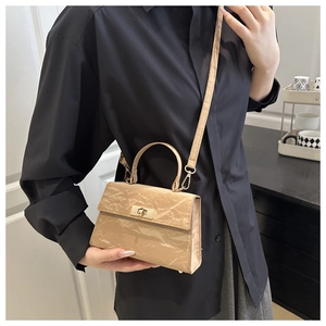 Close-up of beige crossbody bag with pleated paper texture and gold twist lock detail