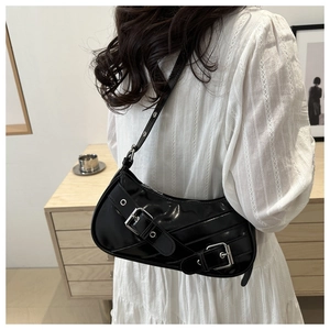 Detail of black glossy crescent bag with twin metal buckles and adjustable strap