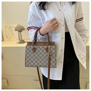 Detail of vintage monogram fabric tote bag featuring brown leather trim and metal buckles