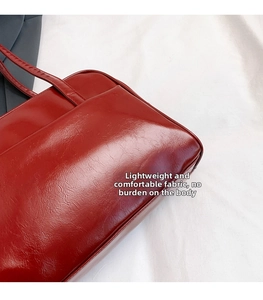 Close-up of retro dark red tote bag with glossy cracked leather texture and side pocket