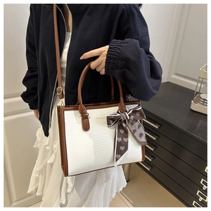 Detail of white snake skin texture bag with brown leather trim and a silk heart scarf