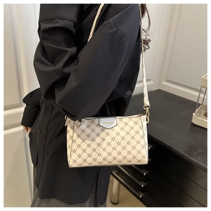 Dettaglio borsa a tracolla beige monogram con placca dorata e gancio in metallo