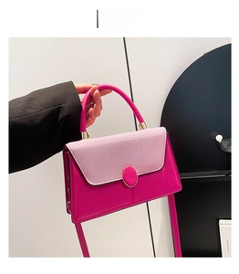 Detail of rose red textured leather tote bag with elegant golden circular metal clasp