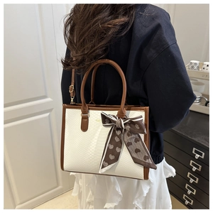 Detail of stone pattern handbag with brown leather trim and heart print silk scarf