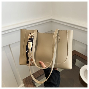 Détail d'un sac cabas beige avec coutures blanches et foulard en soie décoratif noué