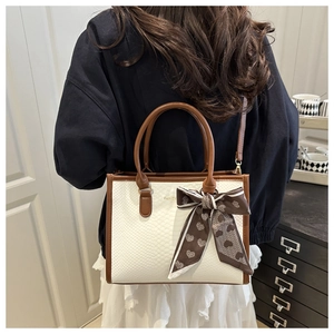 Macro detail of the creamy white crocodile embossed leather bag and heart pattern scarf
