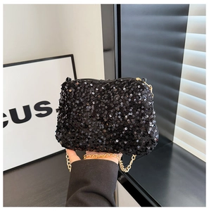 Gros plan sur un sac de soirée à paillettes noires avec chaîne dorée et fermeture éclair