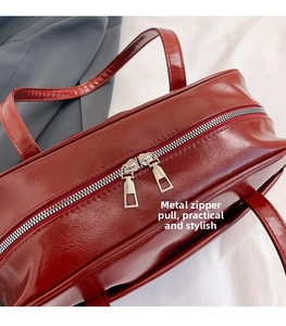 Detail of dark red glossy PU tote bag featuring high-quality silver double zipper closure