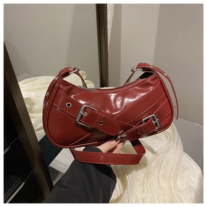 Détail du sac croissant bordeaux au fini brillant avec boucle argentée sur la sangle