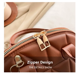 Detail of premium brown quilted handbag showing gold dual metal zippers and leather texture