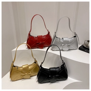 Détail de quatre sacs hobo à nœud colorés en rouge, argent, or et noir sur un support