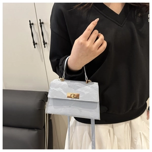 Close-up of light blue textured crossbody bag with gold metal clasp and leather handle