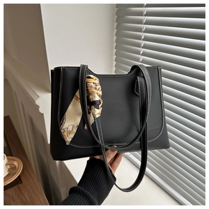 Détail du sac cabas noir avec surpiqûres blanches et foulard en soie décoratif sur l'anse