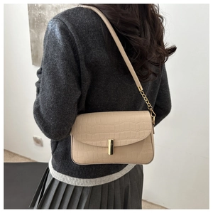 Detail of beige faux crocodile texture shoulder bag with gold metal buckle closure