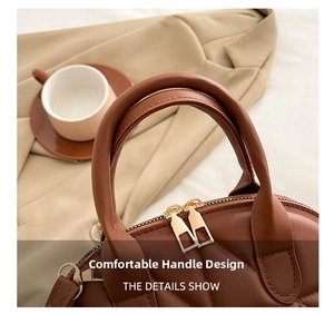 Detail of padded brown handle and golden dual-zipper closure on quilted tote bag