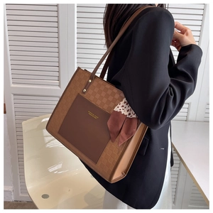 Borsa tote marrone a scacchi con foulard di seta portata a spalla da una modella nel set
