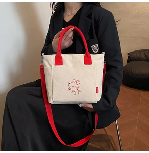 Detail of off-white canvas tote with red handles, cartoon bear print and front pockets