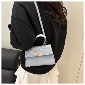 Detail of light blue marble textured handbag with gold twist lock on black sweatshirt