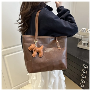 Détail du sac cabas marron vintage avec coutures géométriques et pendentif chien chic
