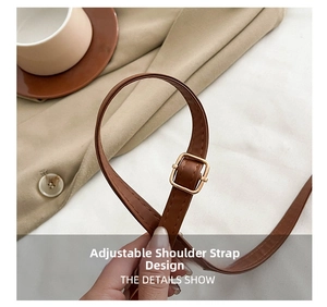 Detail of adjustable brown faux leather shoulder strap with a golden metal pin buckle