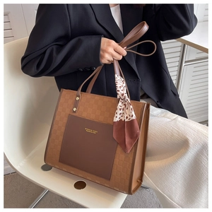 Dettaglio della borsa tote marrone vintage con goffratura a scacchi e foulard di seta