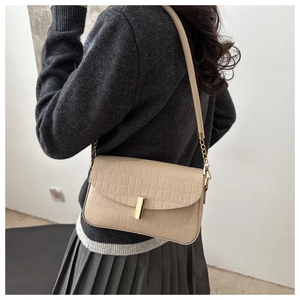 Detail of beige faux crocodile leather shoulder bag with gold clasp and chain strap