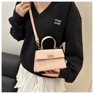 Detailed shot of pink faux leather crossbody bag with crocodile texture and gold hardware
