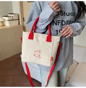 Detail of canvas bucket bag featuring red handles and cute cartoon bear print