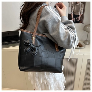 Détail d'un sac cabas noir en patchwork avec bandoulière marron et charm chien